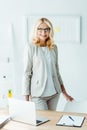 Recruiter in glasses standing near chair in office