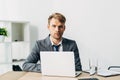 Recruiter looking at camera near laptop and clipboard on table