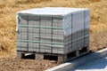 Rectangle grey stone tiles stacked on top of wooden pallet and covered with nylon protection next to gravel sidewalk Royalty Free Stock Photo