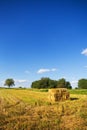 Rectangle shaped bales of straw on farmland with blue beautiful sky, harvesting. Summer sunset, warm light. Royalty Free Stock Photo