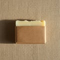 A rectangular bar of handmade soap partially wrapped in brown kraft paper lies on a Royalty Free Stock Photo