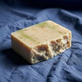 A rectangular bar of handmade soap rests on a textured blue fabric Royalty Free Stock Photo