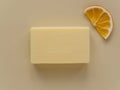 Rectangular bar of soap and slice of dried orange on beige background