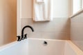 Rectangular bathtub of home bathroom with black curved faucet on the rim Royalty Free Stock Photo