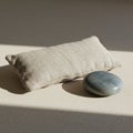 A rectangular beige linen pillow rests on a flat surface alongside a smooth, oval-shape Royalty Free Stock Photo
