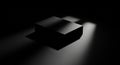 A rectangular black box sits on a dark surface with focused beams of light highlighting its flat Royalty Free Stock Photo