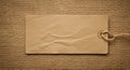 Rectangular, blank paper tag with rounded corners lies on textured burlap surface. Royalty Free Stock Photo