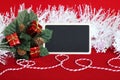 rectangular blank slate to write a message, leaves filled with red gifts, a frosted white wreath and a red and white thread for
