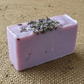 A rectangular block of lavender-colored soap resting on a burlap fabric