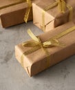 Rectangular box wrapped in brown paper and tied with a silk ribbon with a bow, gift on a gray background Royalty Free Stock Photo