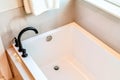 Rectangular built in bathtub with black curved faucet inside bathroom of home Royalty Free Stock Photo