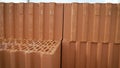 Red clay bricks are stacked on wooden pallets. New bricks on the construction site near the building under construction. Royalty Free Stock Photo