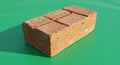 Rectangular clay brick with a reddish-brown hue resting on a green surface. The brick Royalty Free Stock Photo