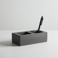 Rectangular concrete pen holder with two compartments sits on a white surface. A Royalty Free Stock Photo