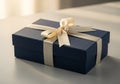 A rectangular, dark blue gift box rests on a smooth surface, adorned with a creamy satin ribbon Royalty Free Stock Photo