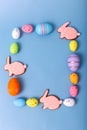 Rectangular frame of multicolored Easter eggs and gingerbread in the form of pink rabbits