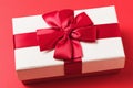 Rectangular gift box with a bow on a red background, close-up