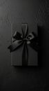A rectangular gift box wrapped in matte black paper lies on a textured, dark surface. It Royalty Free Stock Photo