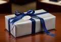 A rectangular gift box wrapped in shimmery silver paper sits on a polished wooden surface. It is Royalty Free Stock Photo