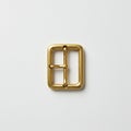 A rectangular, gold-colored metal buckle is centered on a plain white background. The Royalty Free Stock Photo