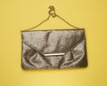 Rectangular golden leather fashion clutch on a metal chain on a yellow background