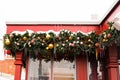 Rectangular green decoration of Christmas tree branches, balls, garlands and icicles on red wooden small house Royalty Free Stock Photo