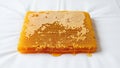 A rectangular honeycomb filled with golden honey rests on a white surface Royalty Free Stock Photo
