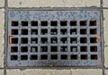 Metal storm drain grate set into a concrete sidewalk with square Royalty Free Stock Photo