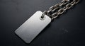 Rectangular metal tag attached to a sturdy chain placed on a dark, textured surface. The tag has a Royalty Free Stock Photo