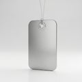 Rectangular metal tag with rounded corners, featuring a brushed texture. Suspended by a thin wire Royalty Free Stock Photo