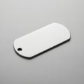 Rectangular metallic plate, resembling a military dog tag, on a smooth gray surface. Features Royalty Free Stock Photo