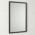 A rectangular mirror with a slim black frame is mounted on a lightly textured white wall. Royalty Free Stock Photo