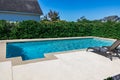 A rectangular new swimming pool with tan concrete edges in the fenced backyard of a new construction house Royalty Free Stock Photo