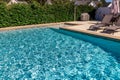 A rectangular new swimming pool with tan concrete edges in the fenced backyard of a new construction house Royalty Free Stock Photo