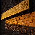 Rectangular perforated metal panel mounted on a brick wall, casting intricate Royalty Free Stock Photo