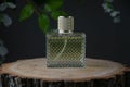 A rectangular perfume bottle on a slice of oak. Flowers on the background