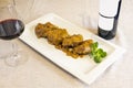 rectangular plate with a portion of stewed cheeks next to a glass and bottle of red wine