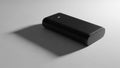 Rectangular power bank is placed on a smooth light gray surface casting a Royalty Free Stock Photo