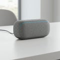A rectangular smart speaker with rounded edges is positioned on a white table. Its Royalty Free Stock Photo