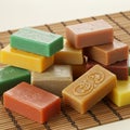 Rectangular soaps in various colorsâgreen, yellow, orange, beigeâare stacked on a bamboo mat. Royalty Free Stock Photo