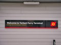 A rectangular welcome sign with corporate logo at the Tarbert Ferry Terminal on the Isle of Harris in the Outer Hebrides, Scotland