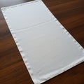 A rectangular white fabric placemat is laid out on a dark wooden table. The placemat Royalty Free Stock Photo