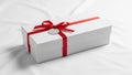 A rectangular white gift box sits on a smooth white fabric surface Royalty Free Stock Photo