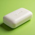 Rectangular white soap bar with rounded edges rests on a light green surface. \