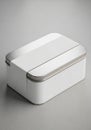 A rectangular white tin box with a brushed silver lid and rounded edges sits on a gra Royalty Free Stock Photo