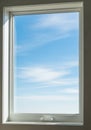 A rectangular window with a white frame captures a view of a blue sky dotted with wis Royalty Free Stock Photo