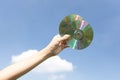 Recyclable CD disk held in hand up on sky-like isolated background. Gyre