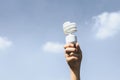 Recyclable light bulb held in hand up on sky-like isolated background. Gyre