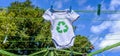 Recycle clothes icon on Babygro drying outside on washing line with 100% Recycled text