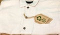 Recycle clothes icon on label with 100% Recycled fabric text. Sustainable fashion